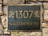 Brass house number sign with '1307 N WETHERLY DR' on a stone wall.